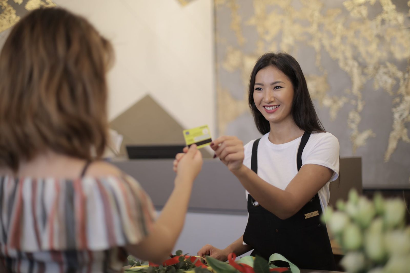 A florist smiling as she takes a card payment from a customer in her flower shop