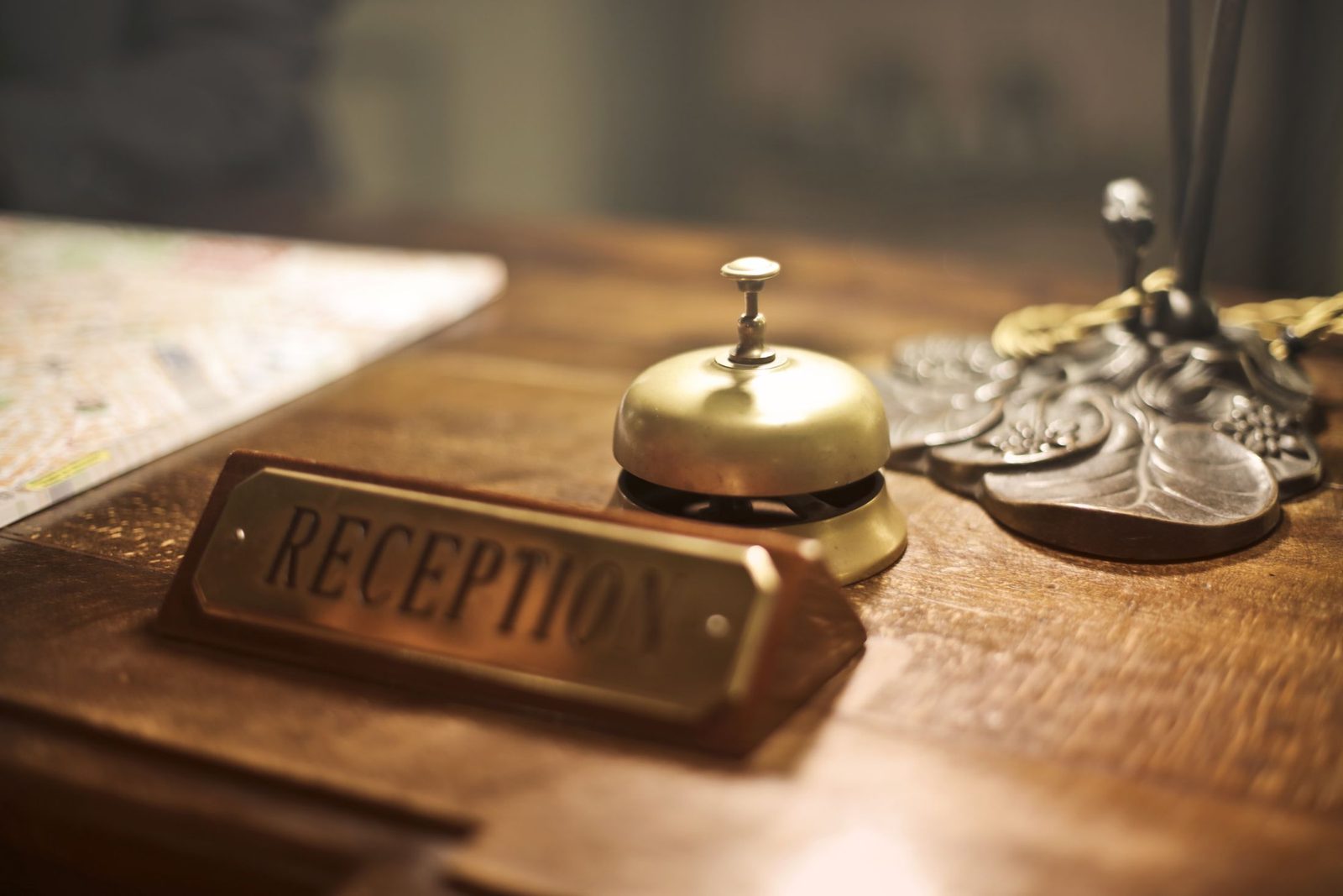 A brass service bell and reception sign on a wooden hotel counter