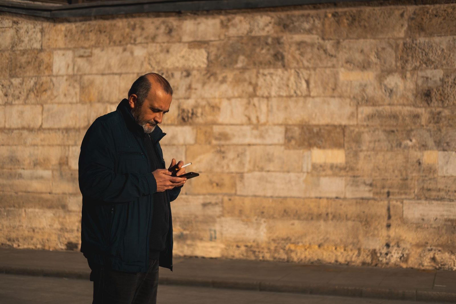 A man checking his phone on a high street pavement