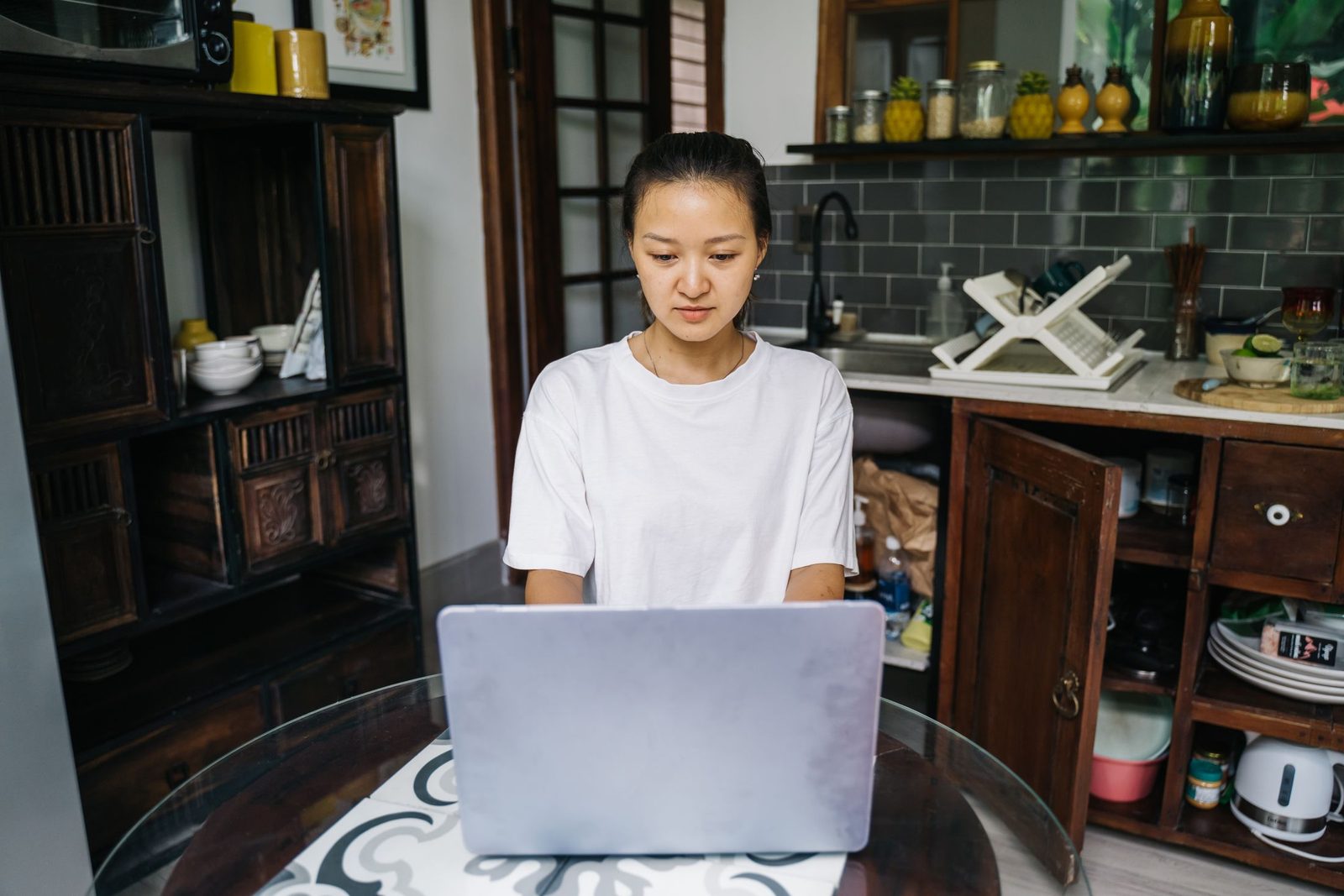A woman working on her laptop at a tidy kitchen table