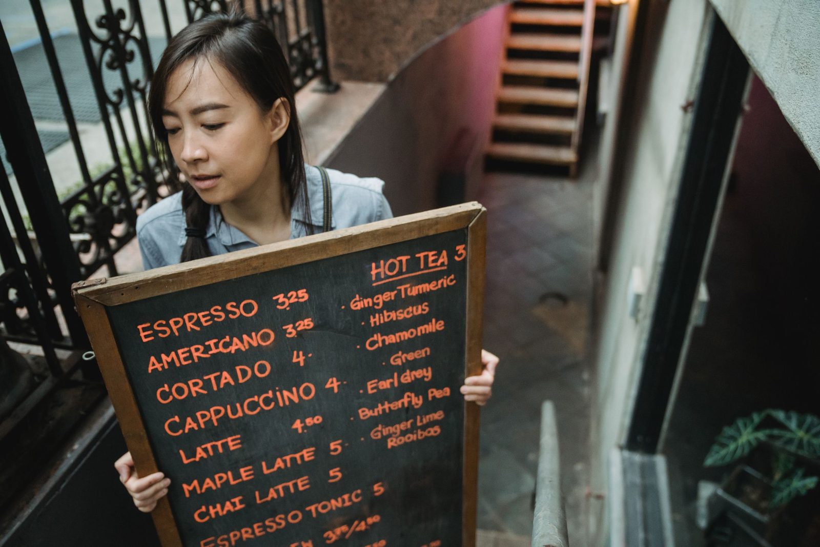 A barista holding a chalkboard menu outside a café