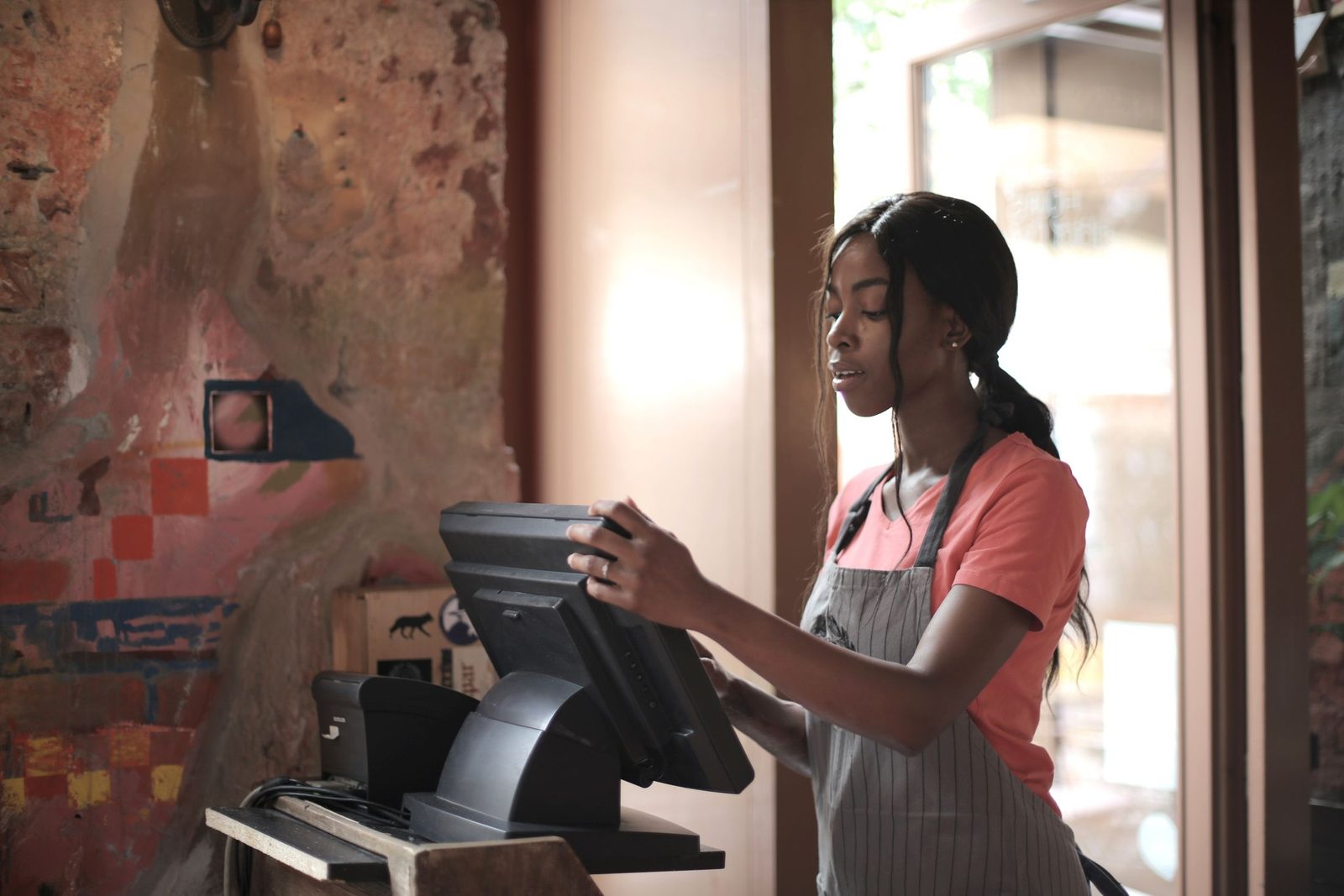 A shop assistant serving at the till in a small independent shop