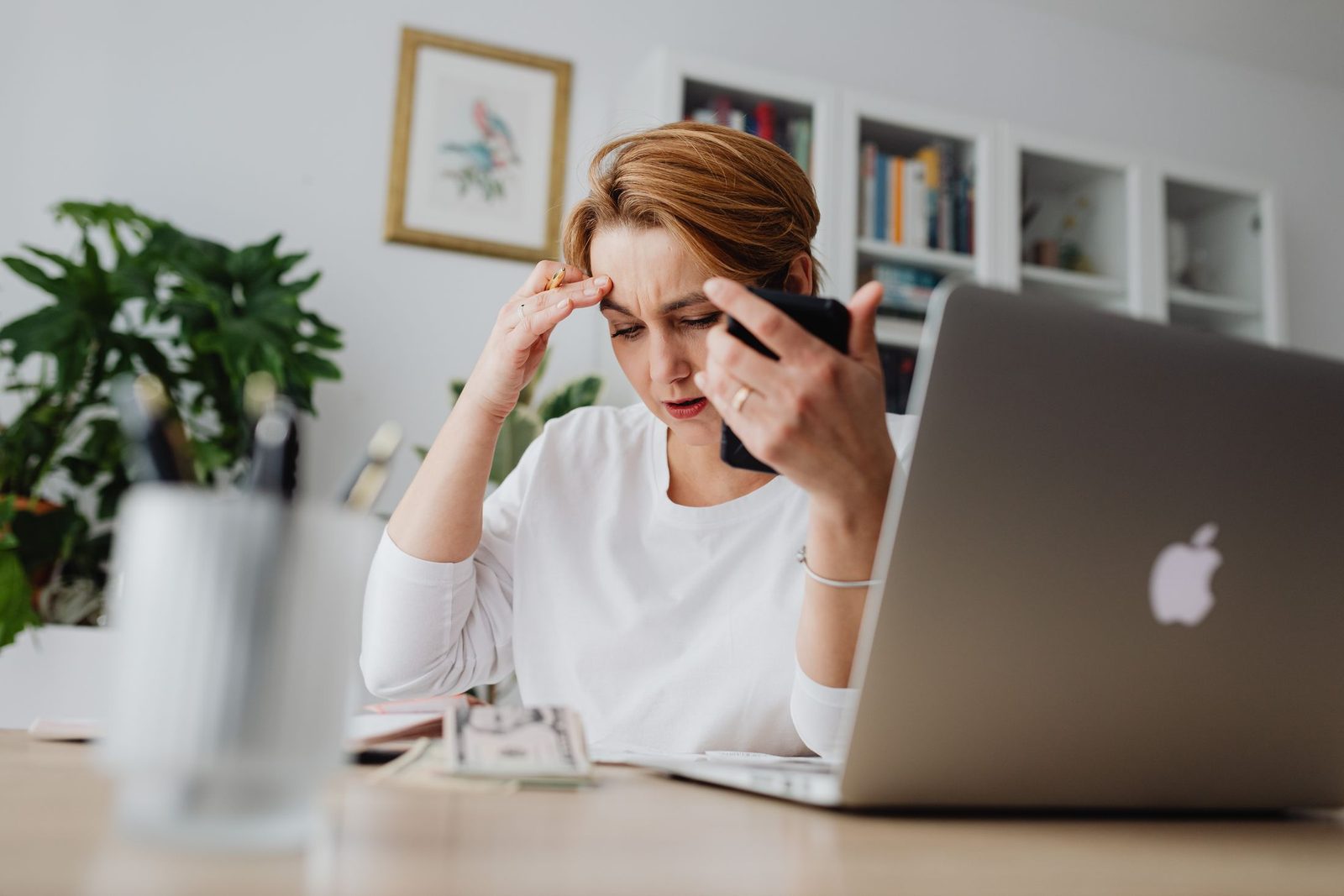 A worried woman looking at her phone at her desk