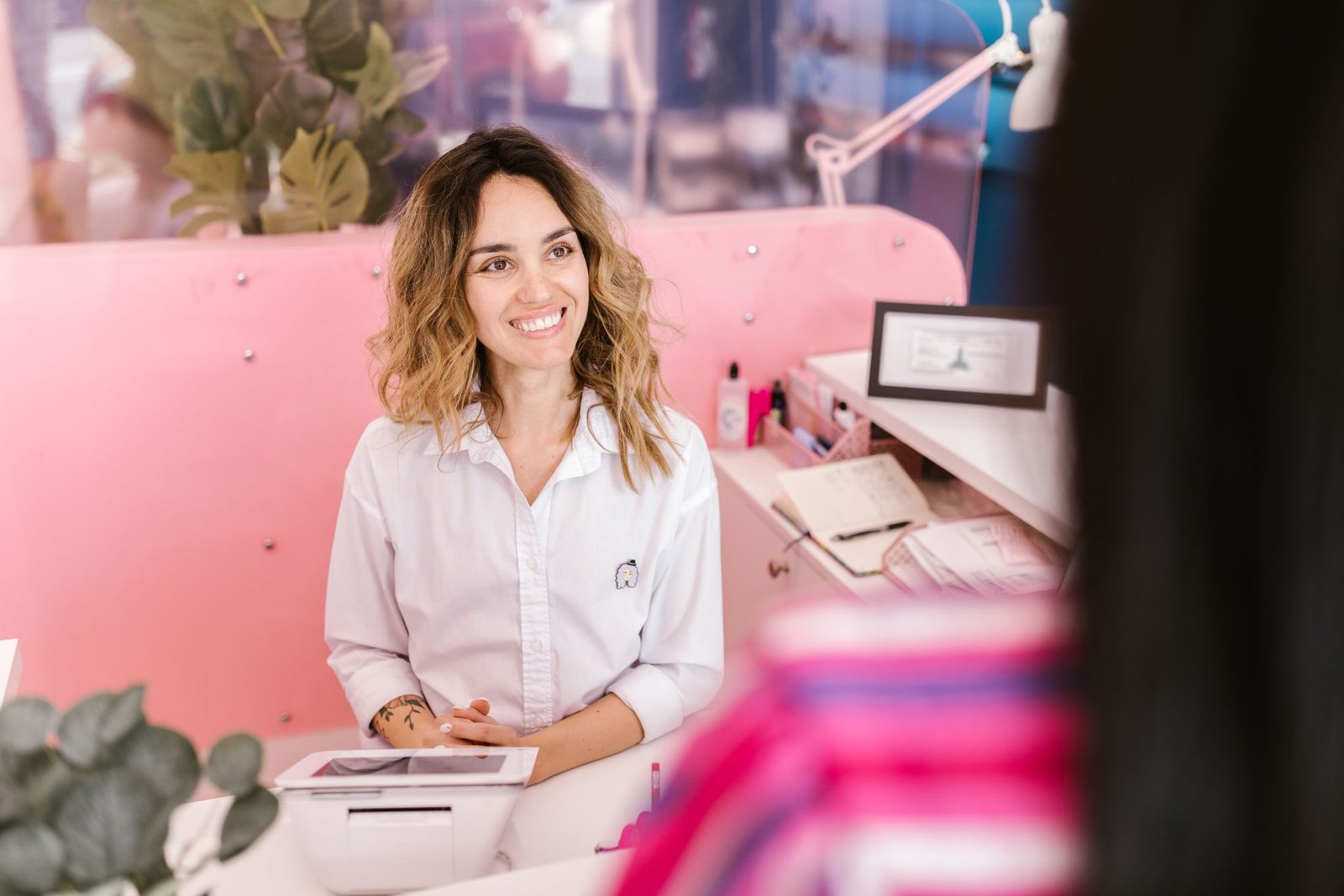 A smiling receptionist at a salon front desk