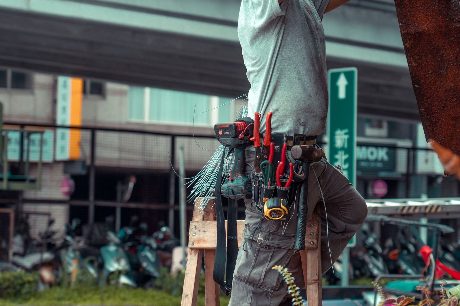 A handyman with a tool belt working up a ladder
