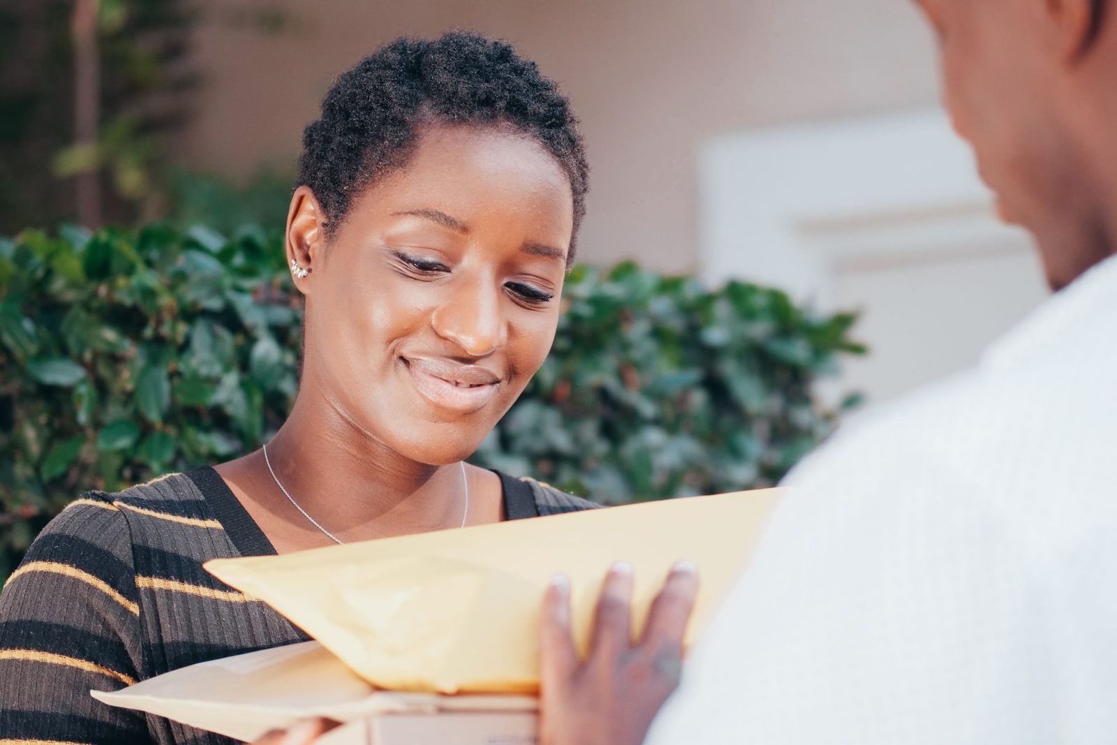 A smiling woman taking a parcel from a courier