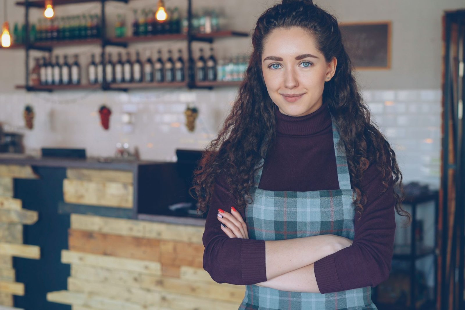 A café owner standing with arms crossed in her café
