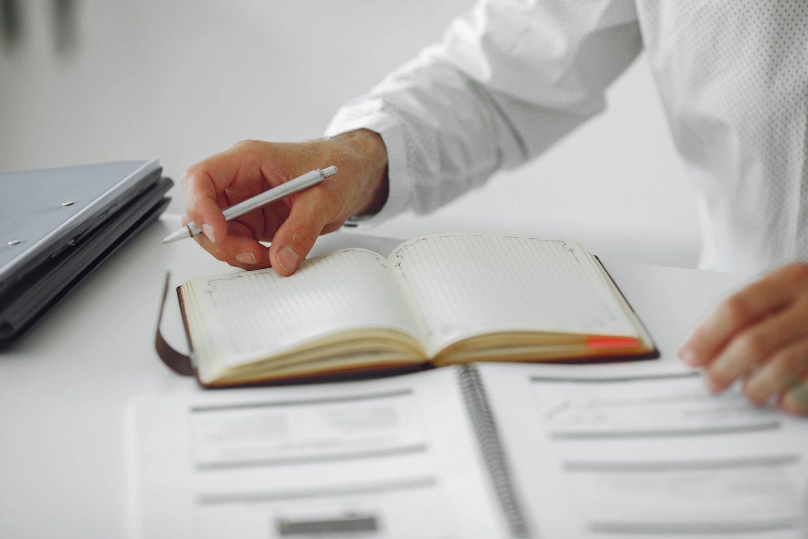 A business owner writing notes in a diary at a desk