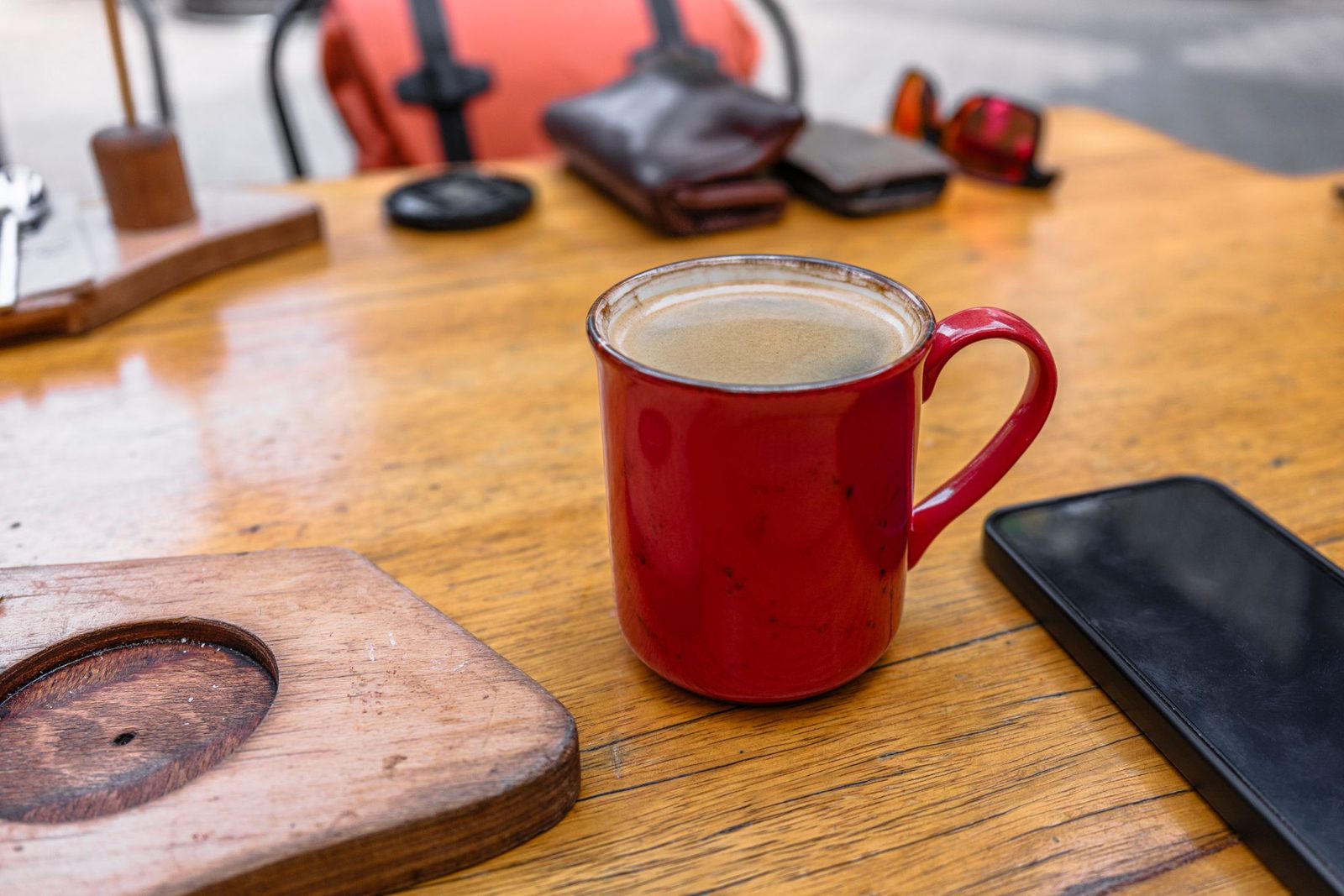 A coffee mug and a phone on a wooden café table