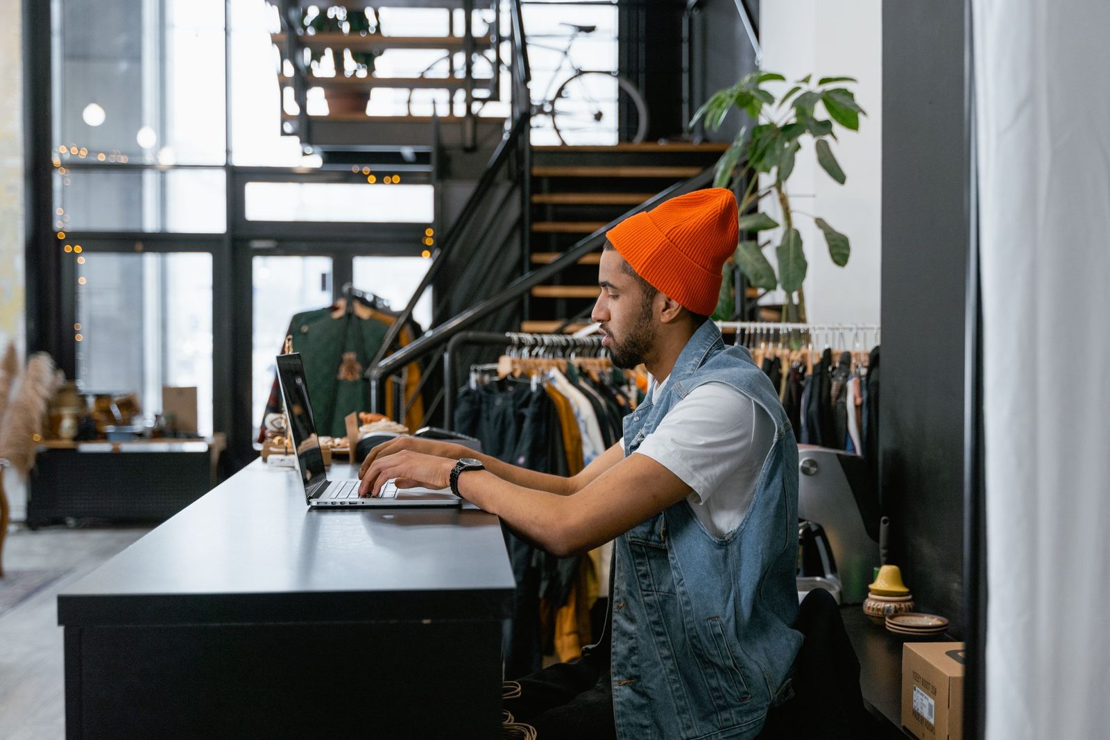 A clothes shop owner sitting at the counter typing on a laptop