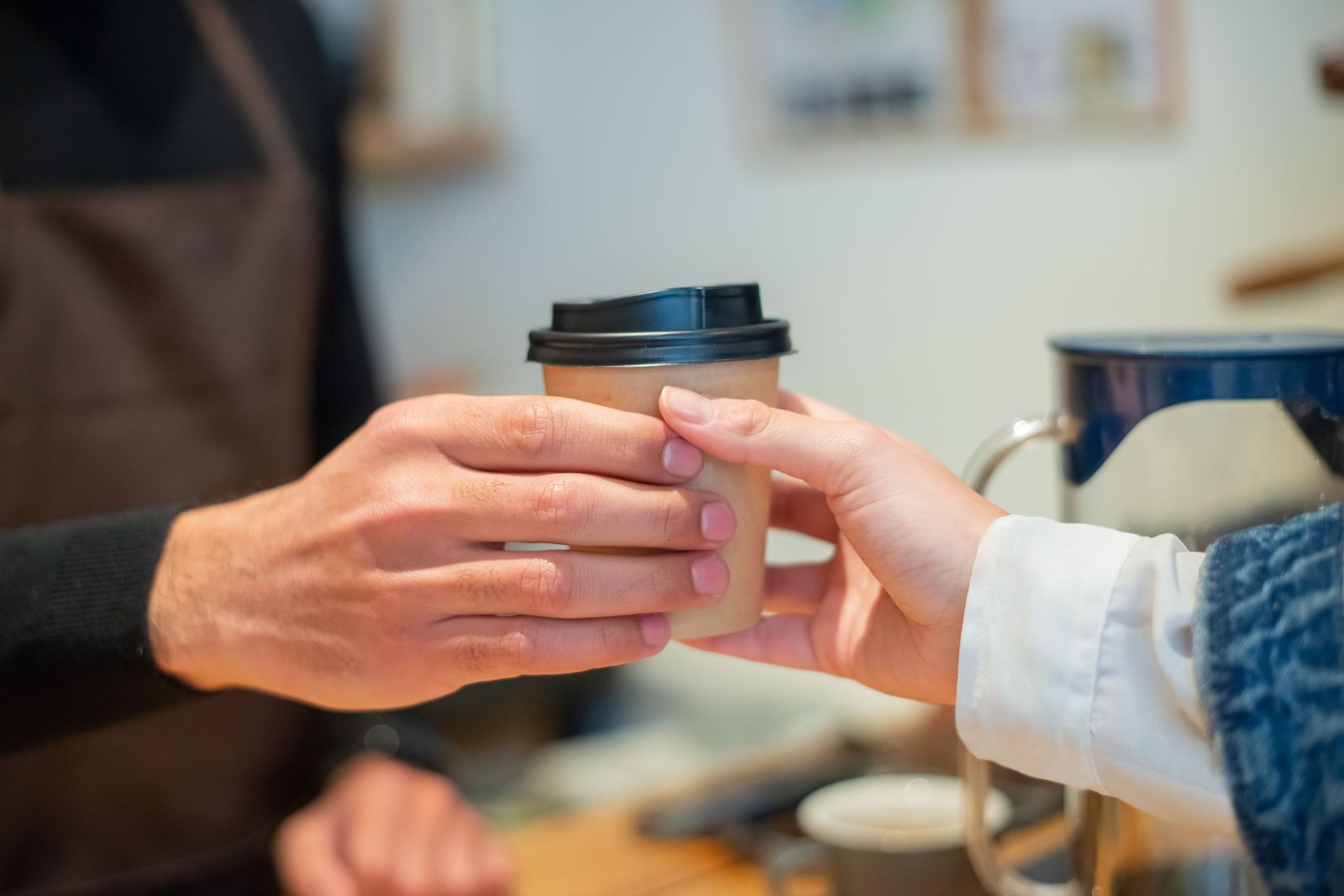A barista handing a takeaway coffee to a customer