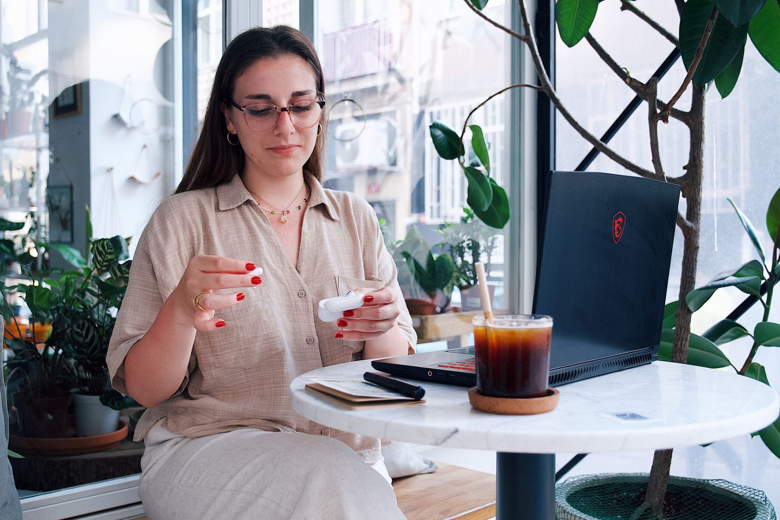 A woman working on a laptop with a coffee in a bright café
